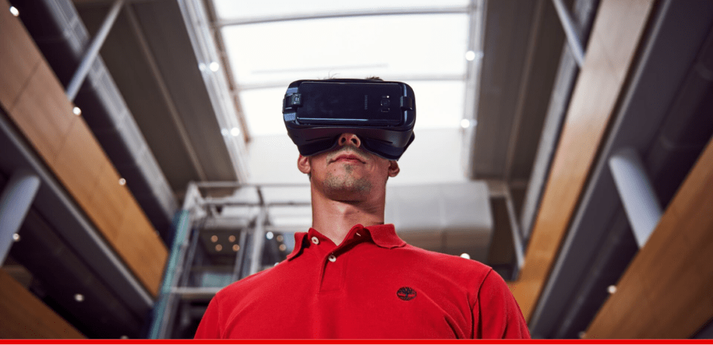 Man wearing a red shirt, wearing a virtual reality headset.