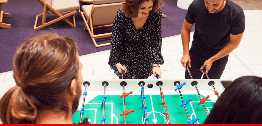 Four colleagues playing table football and smiling.