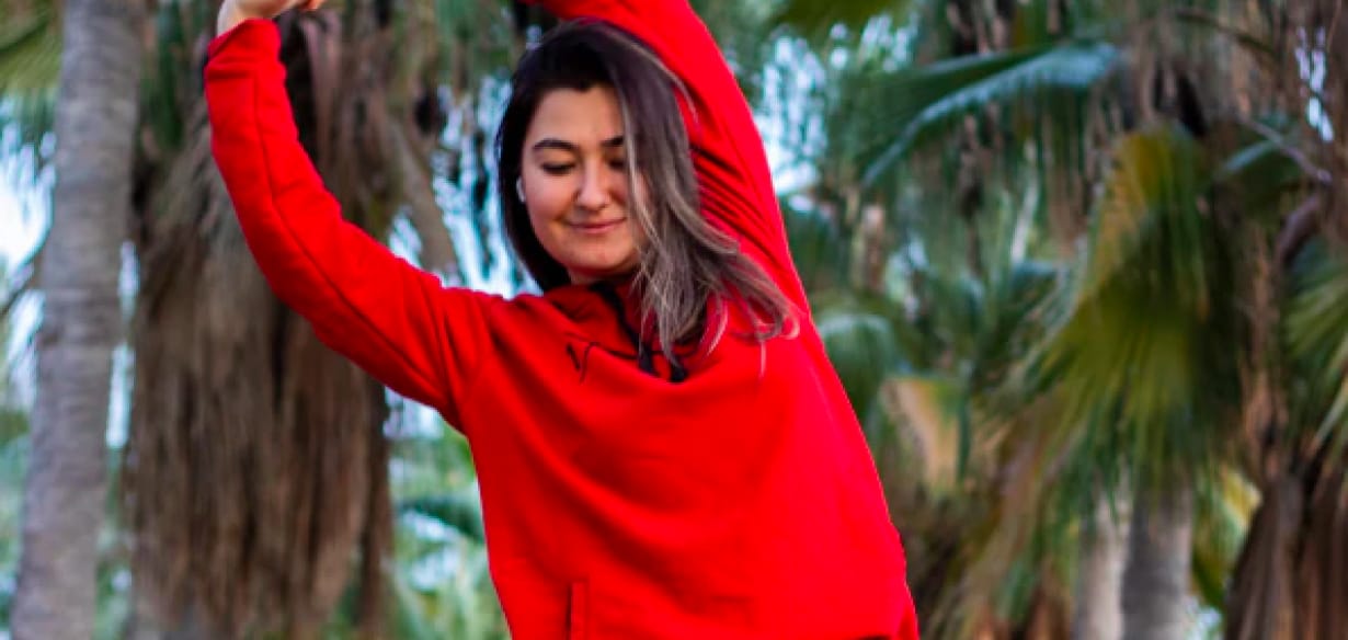 Woman in red top in front of trees.