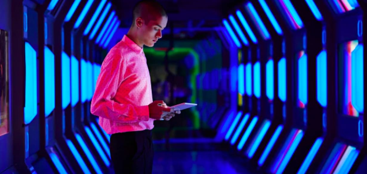 Man standing in lit hallway, looking at an ipad.