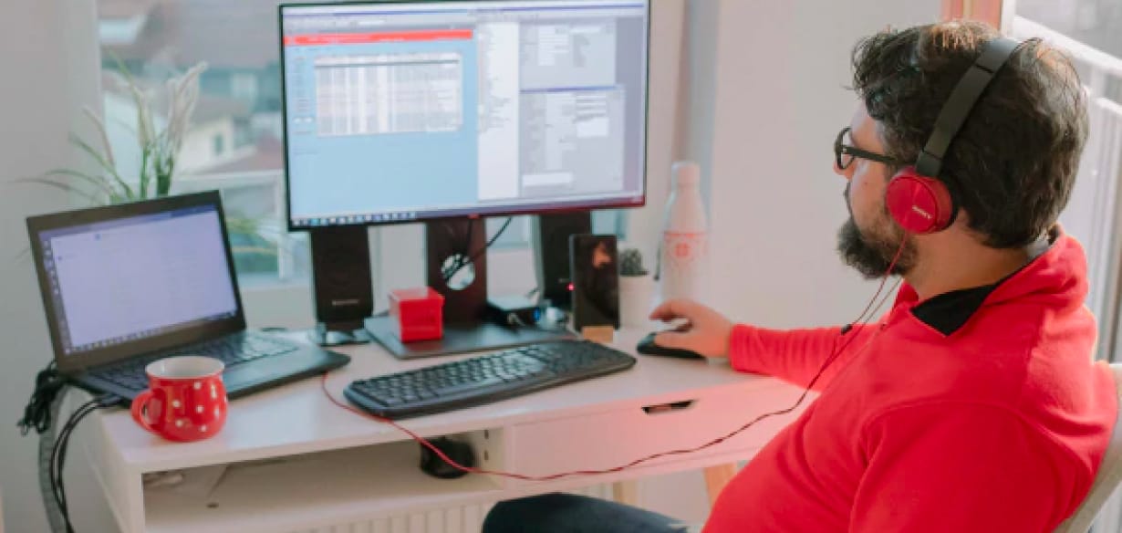 Man wearing headphones working at a desk in his home.