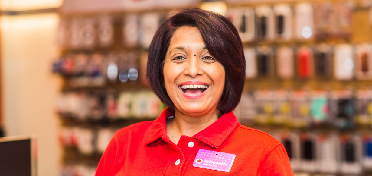 Woman in a red shirt and name tag smiling.