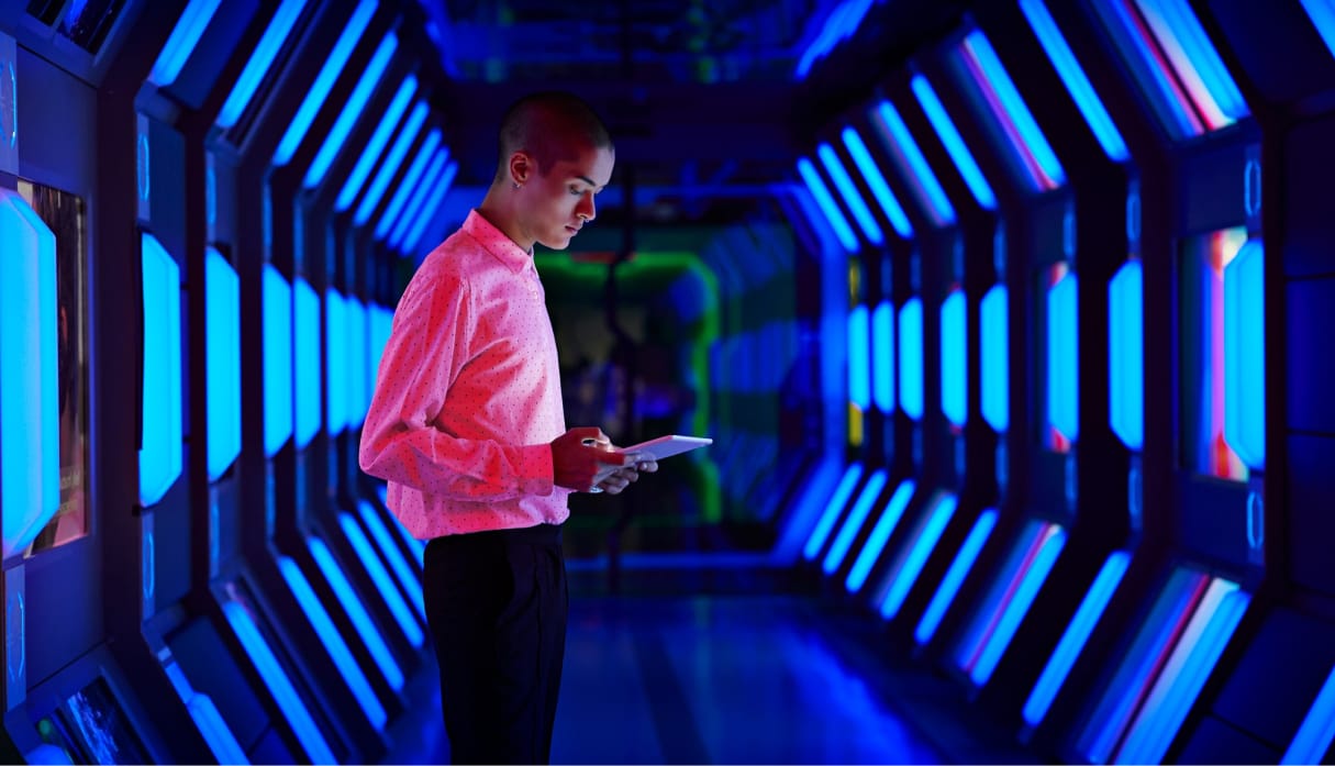 Man standing in lit hallway, looking at an ipad.