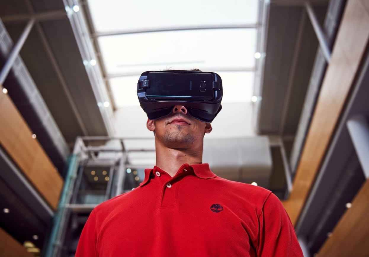 Man in a red shirt wearing a virtual reality headset.