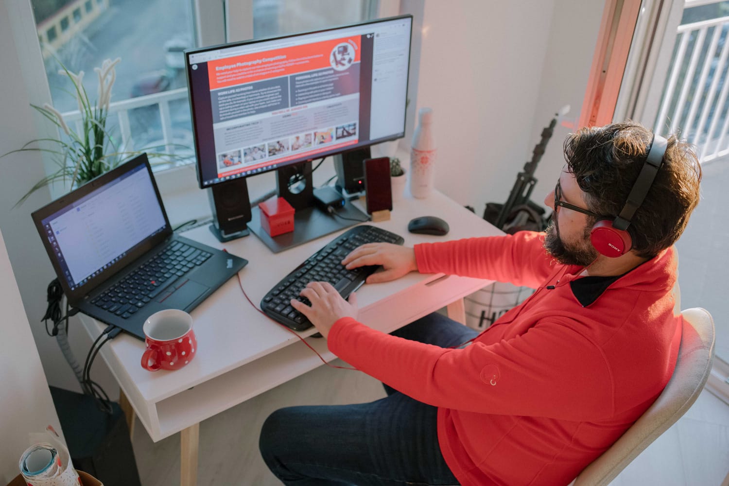 Man wearing red shirt working at his computer at home.