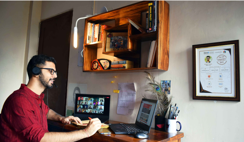 Man seated at a desk wearing headphones, on a video call.