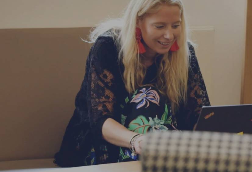 Woman with blonde hair smiling at laptop.